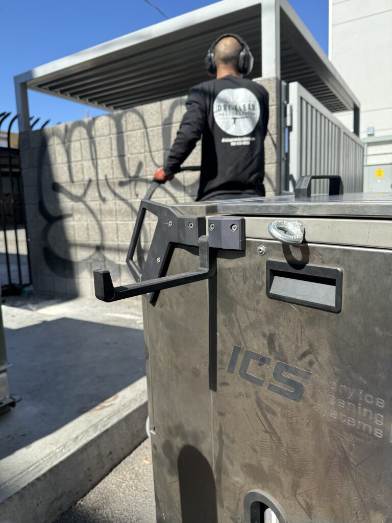 A worker from Dri-Clean Restorations removes graffiti from a cinder block dumpster enclosure in Las Vegas.